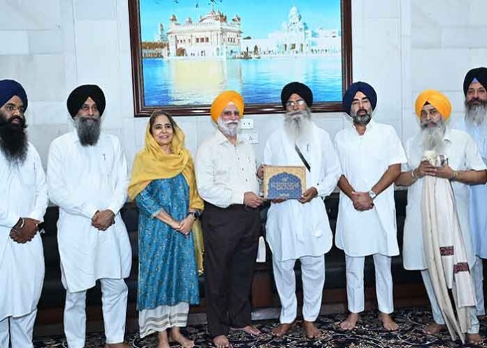 Rupinder Singh presents book to SGPC chief Dhami in Amritsar.